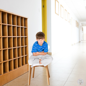 Boy sitting on a chair in hallway.